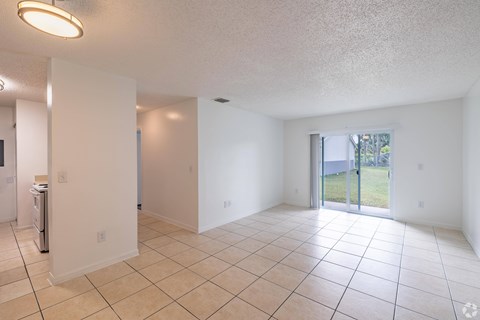 A spacious room with tiled flooring and a sliding glass door leading to a backyard.