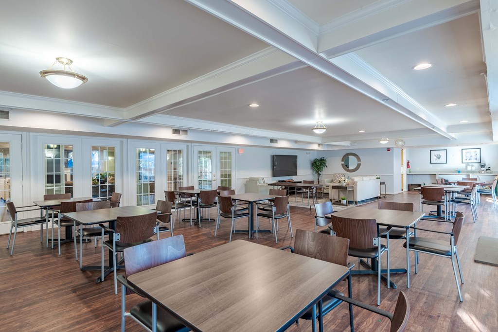 A large room with tables and chairs and a TV.