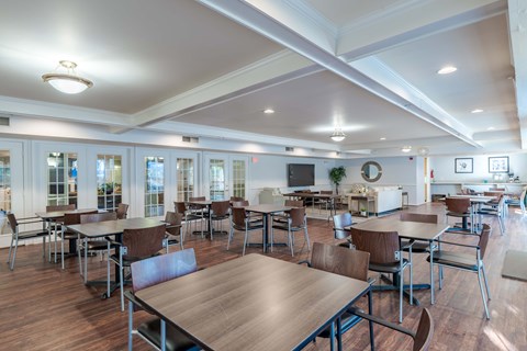 A large room with tables and chairs and a TV.