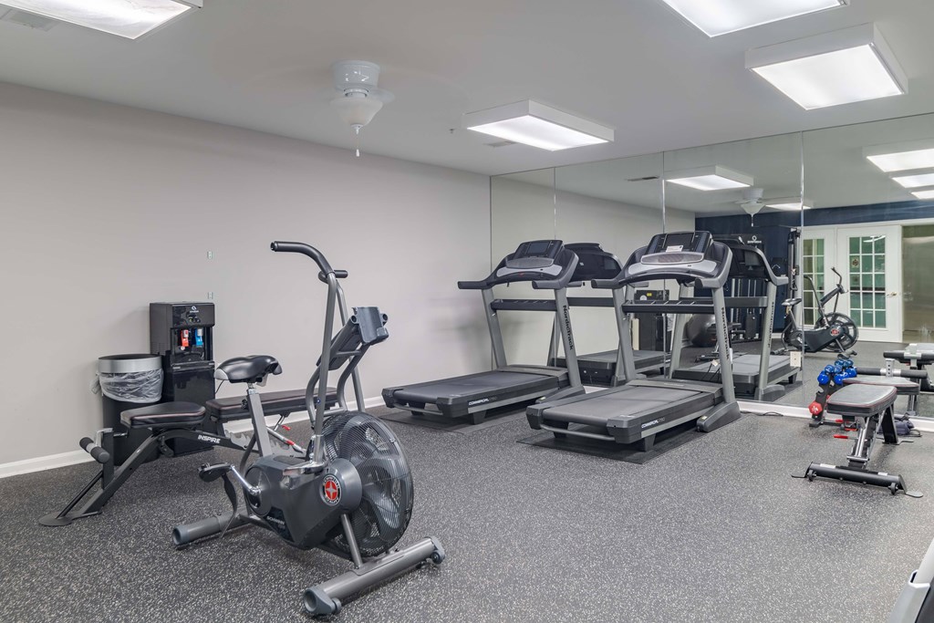 A gym with a variety of equipment including treadmills, stationary bikes, and weight machines.