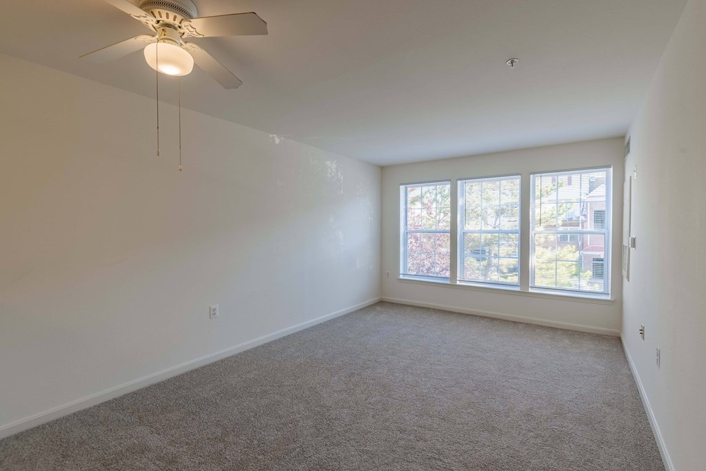 A room with a ceiling fan and carpeted floor.