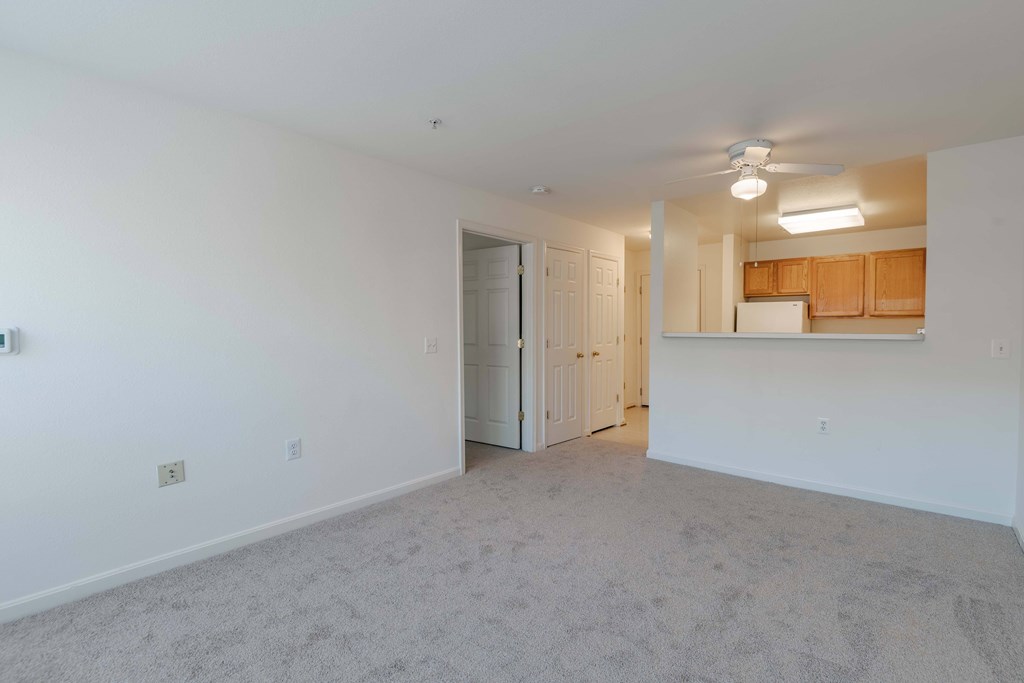 A spacious room with a ceiling fan and a door leading to another room.