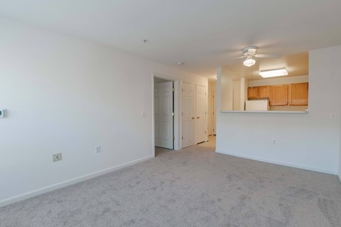 A spacious room with a ceiling fan and a door leading to another room.