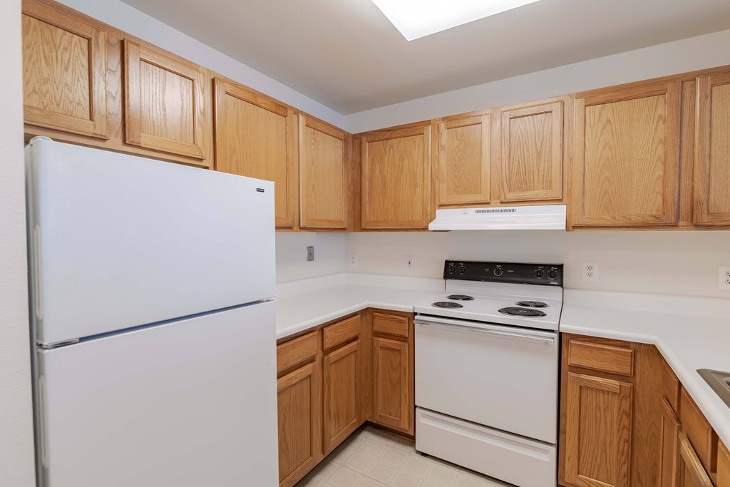 A kitchen with wooden cabinets and white appliances.