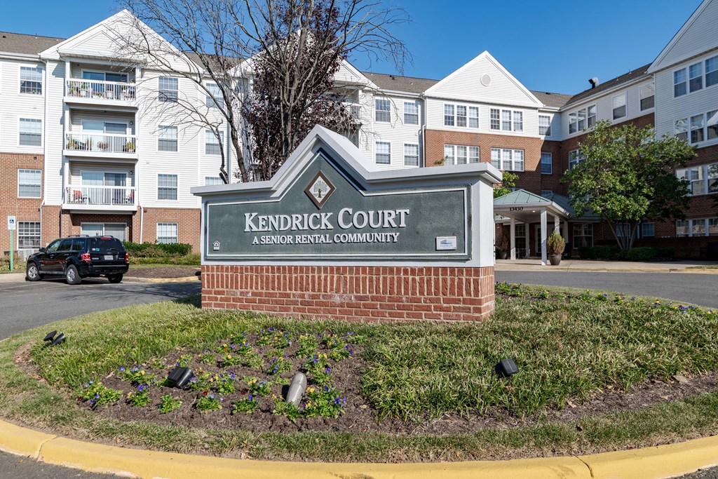 A sign for Kendrick Court Senior Rental Community in front of apartment buildings.