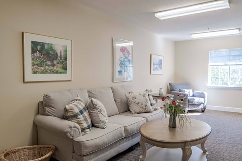 A living room with a couch, a coffee table, and two pictures on the wall.