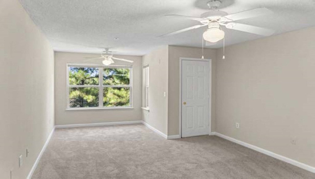 an empty living room with a ceiling fan and a window