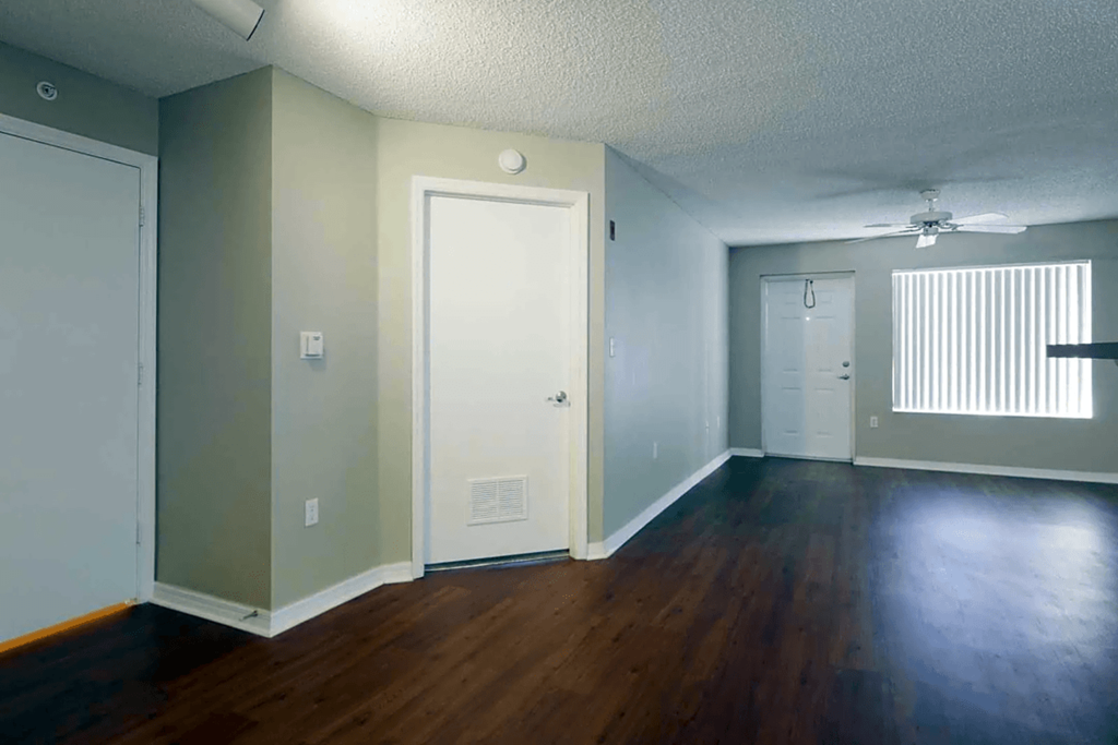 an empty living room with wood floors and a white door