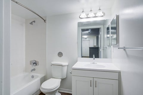 A white bathroom with a toilet, sink, and mirror.