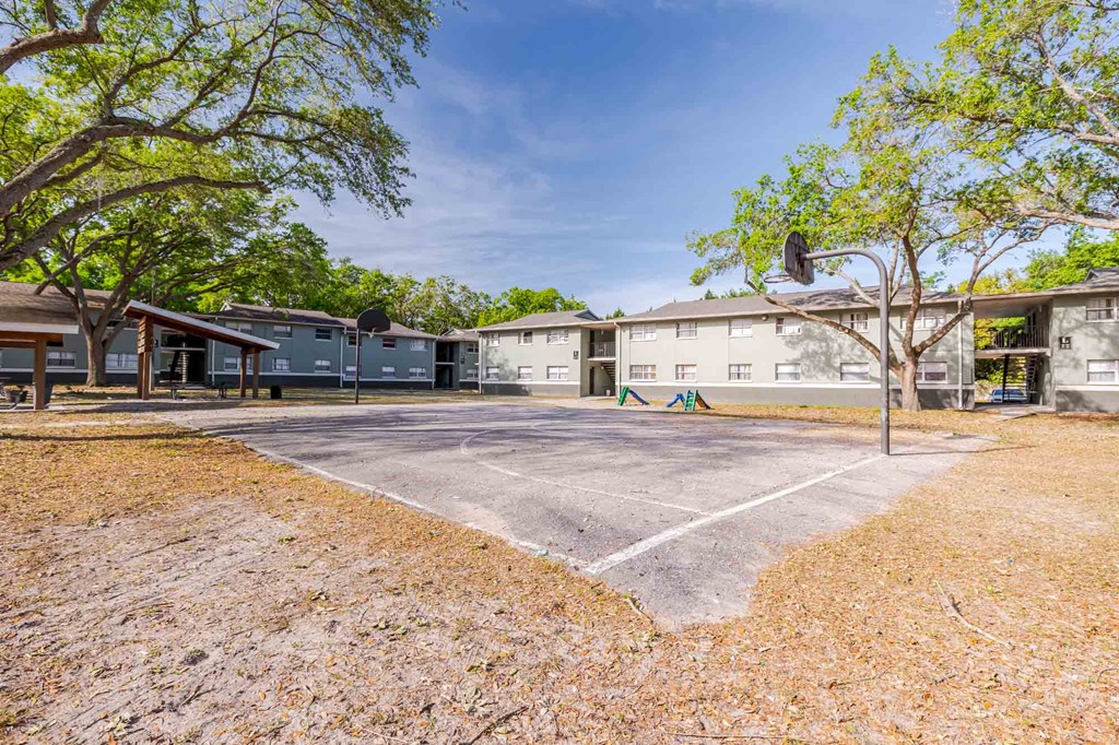A parking lot in front of a building with trees on the sides.