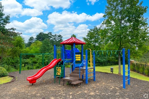 a playground with a red slide and blue playset