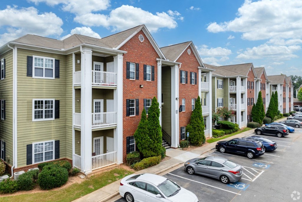 a row of apartment buildings with cars parked in a parking lot at Magnolia Lake Apartments, Carrollton, GA, 30117
