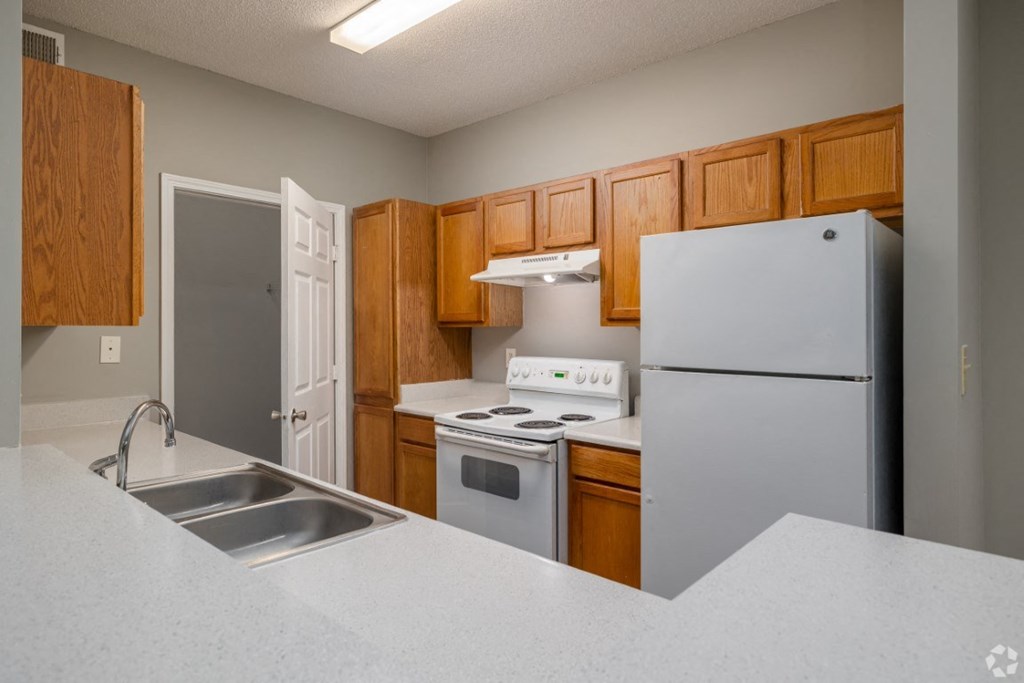 a kitchen with white appliances and wooden cabinets at Magnolia Lake Apartments, Georgia