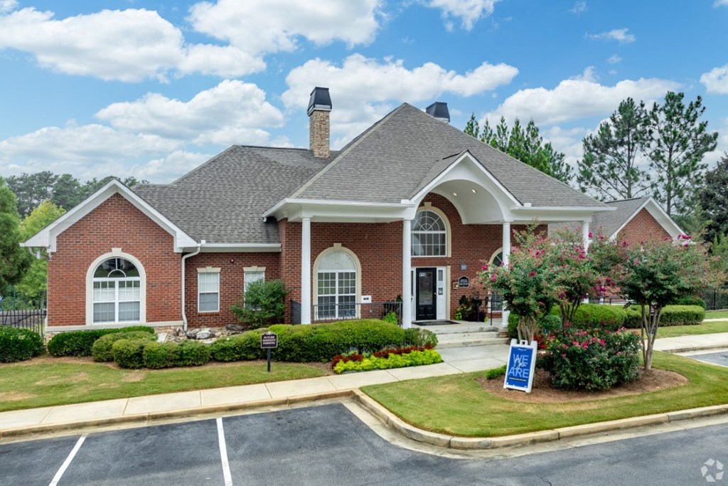 the front of a brick house with a sign in the front yard at Magnolia Lake Apartments, Carrollton, 30117