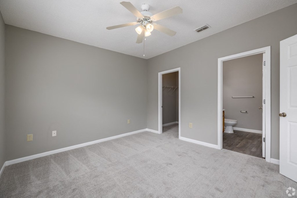 an empty living room with a ceiling fan and a door to a bathroom at Magnolia Lake Apartments, Carrollton