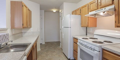 A kitchen with white appliances and wooden cabinets.