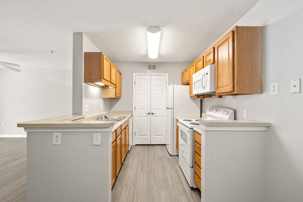 a kitchen with white appliances and wooden cabinets at Palms on Ashley River Apartments, Ladson, SC