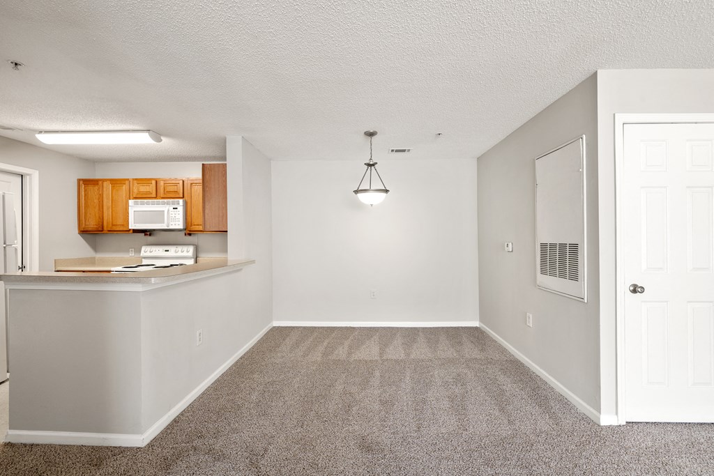 an empty kitchen and dining room with a white door and chandelier at Palms on Ashley River Apartments, Ladson, SC