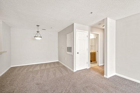 a spacious living room with carpet and a door to a bathroom