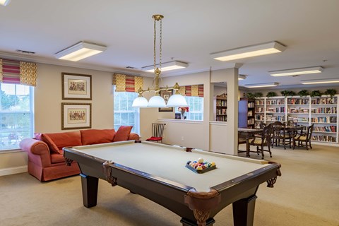 A pool table is in the middle of a room with a couch and a chair.
