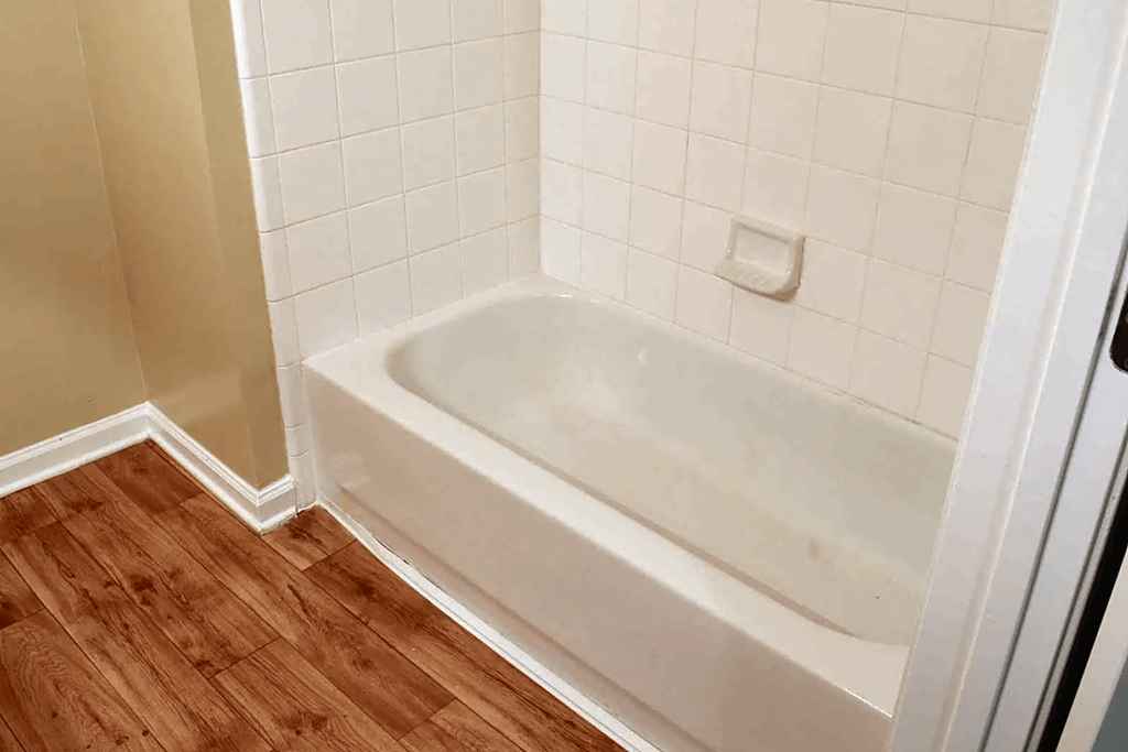 a white bath tub in a bathroom with a wooden floor