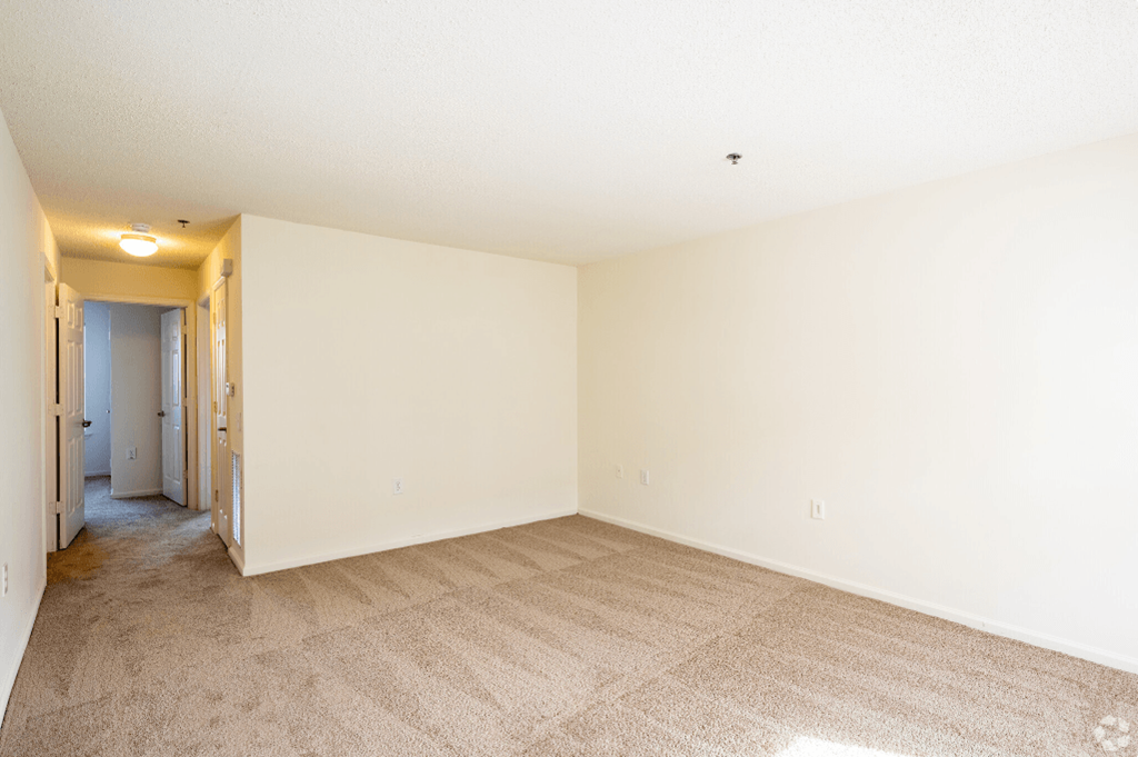 a spacious living room with carpet and white walls
