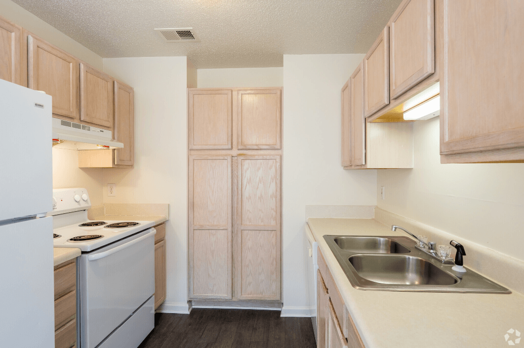 an empty kitchen with white appliances and wooden cabinets
