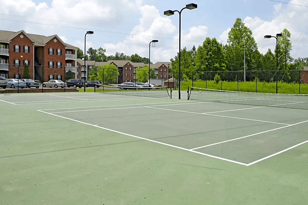 a tennis court with apartments in the background
