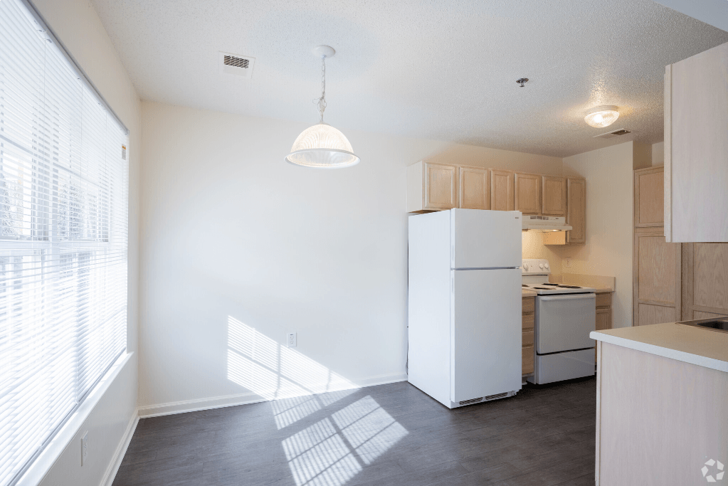 an empty kitchen with a refrigerator and a window