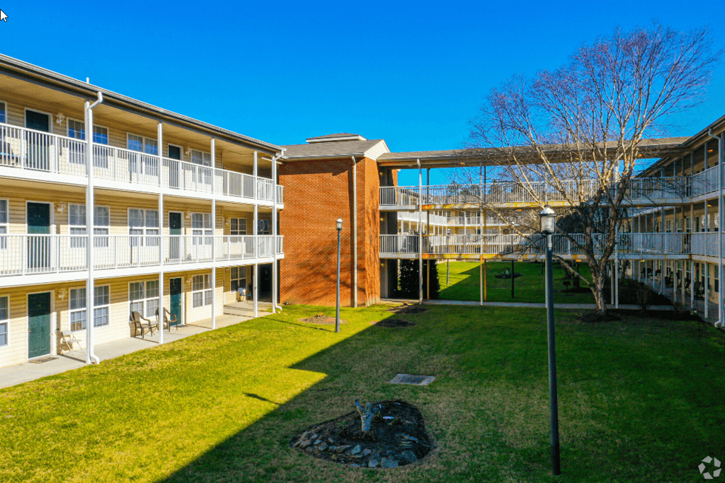 an exterior view of an apartment building with green grass and a tree