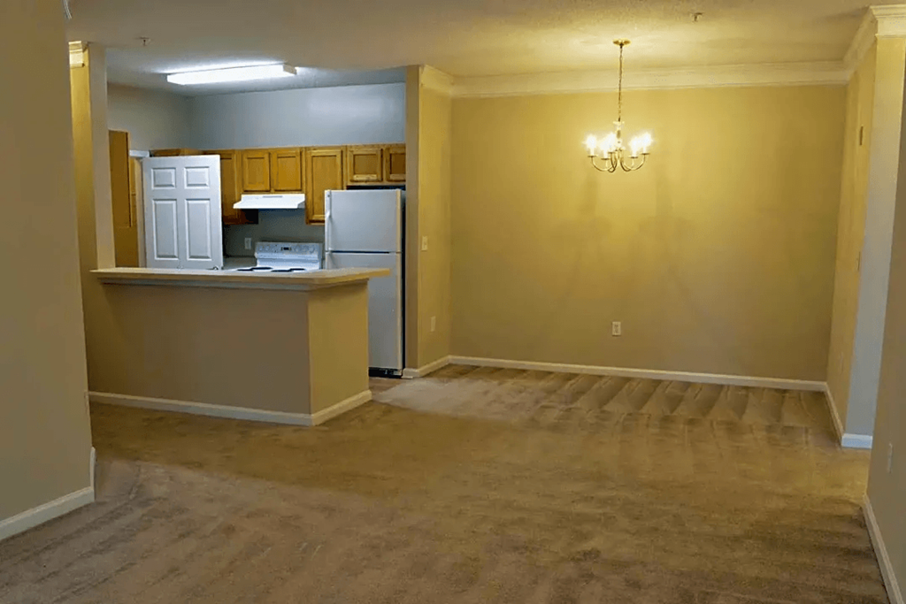 an empty living room and kitchen with a refrigerator and a sink