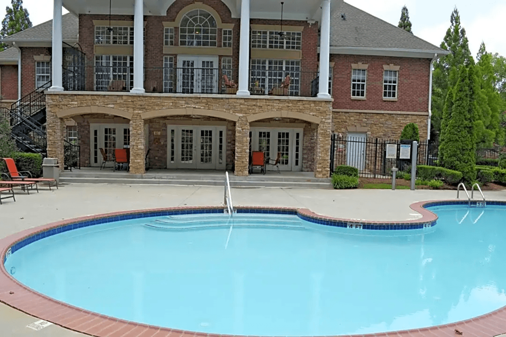 a swimming pool in front of a house with a resort style pool