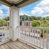 A white railing on a wooden deck overlooks a street.