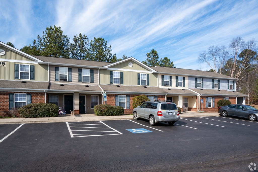 an apartment building with a parking lot and cars in front of it at Pendleton Townhomes Apartments, Durham, 27703