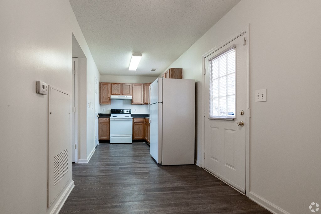 an empty kitchen with white appliances and wood floors at Pendleton Townhomes Apartments, Durham