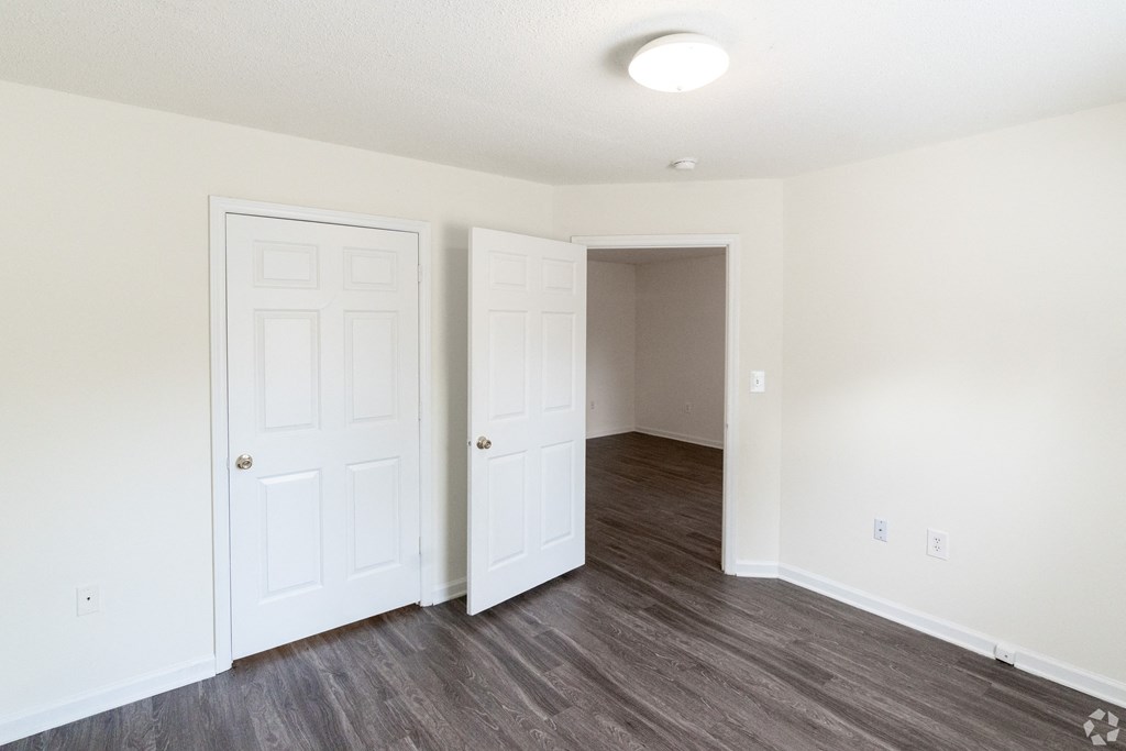 an empty bedroom with white walls and wood flooring at Pendleton Townhomes Apartments, North Carolina