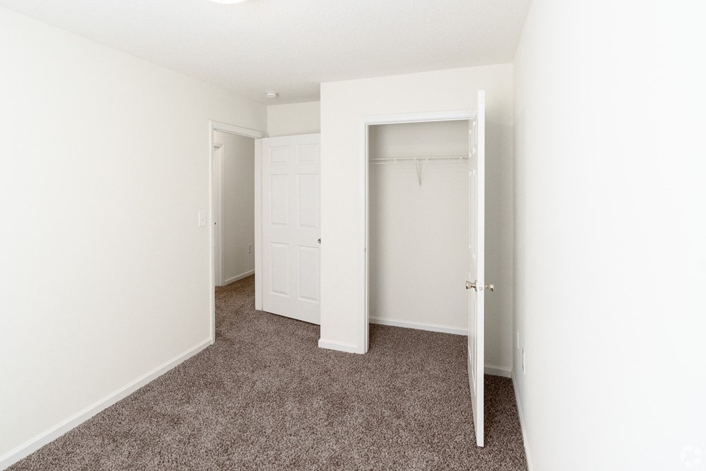 an empty bedroom with white walls and carpet and a closet at Pendleton Townhomes Apartments, North Carolina 27703