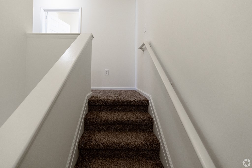 a stairwell with carpeted stairs leading up to a window at Pendleton Townhomes Apartments, Durham, NC