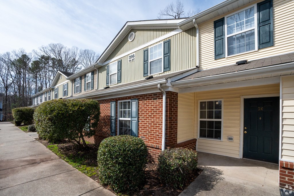 an apartment building with a sidewalk in front of it at Pendleton Townhomes Apartments, North Carolina 27703