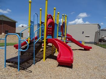 A playground with a red slide and a blue and yellow structure.