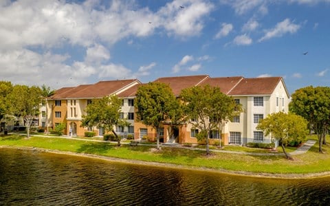 a group of apartment buildings on a grassy area next to a body of water