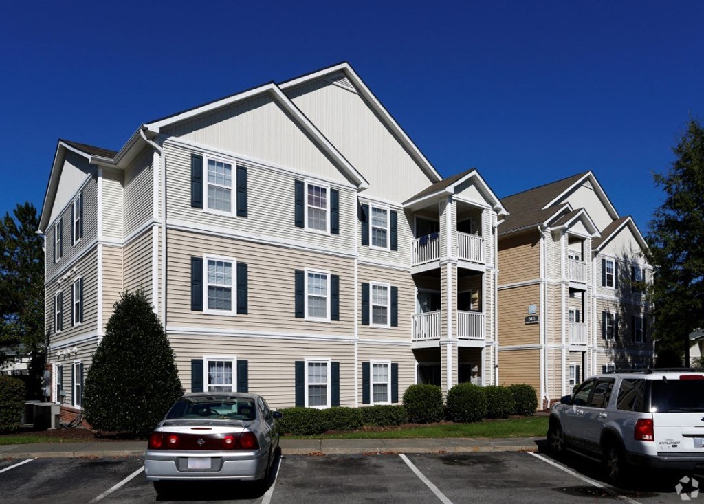 the exterior of an apartment building with cars in a parking lot at Avon Crossings, Durham