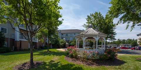 a white gazebo in the middle of a yard with flowers at River Run, Woodbridge, VA  