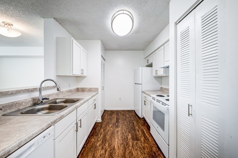 A kitchen with white cabinets and a wooden floor.