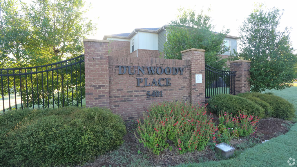 a brick sign in front of a building with a gate