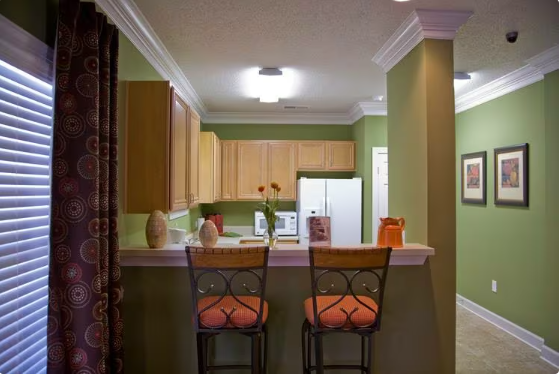 a kitchen with a bar with three chairs