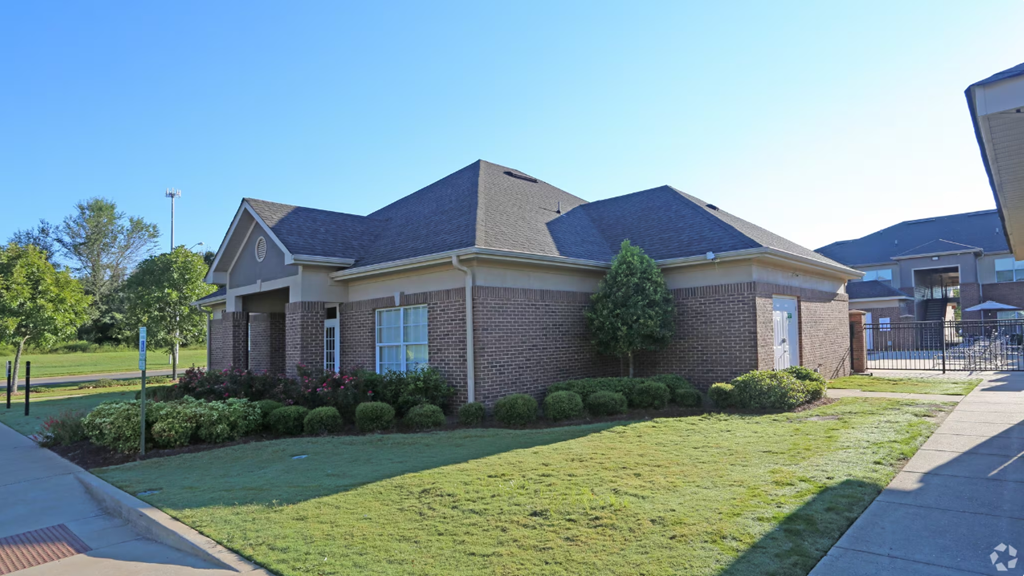 the front of a brick house with a yard and grass
