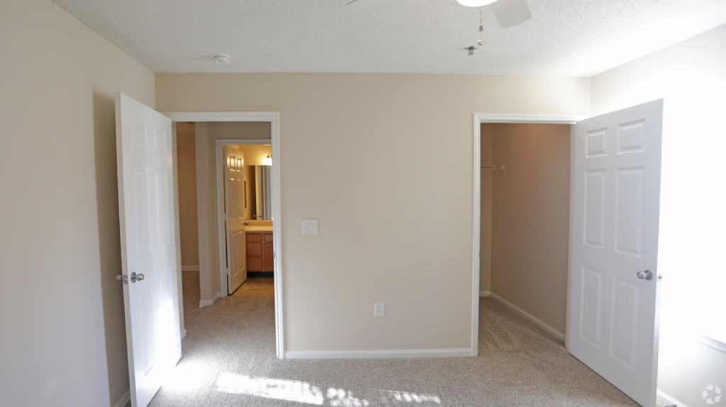 a bedroom with two closets and a hallway leading to a bathroom and a door