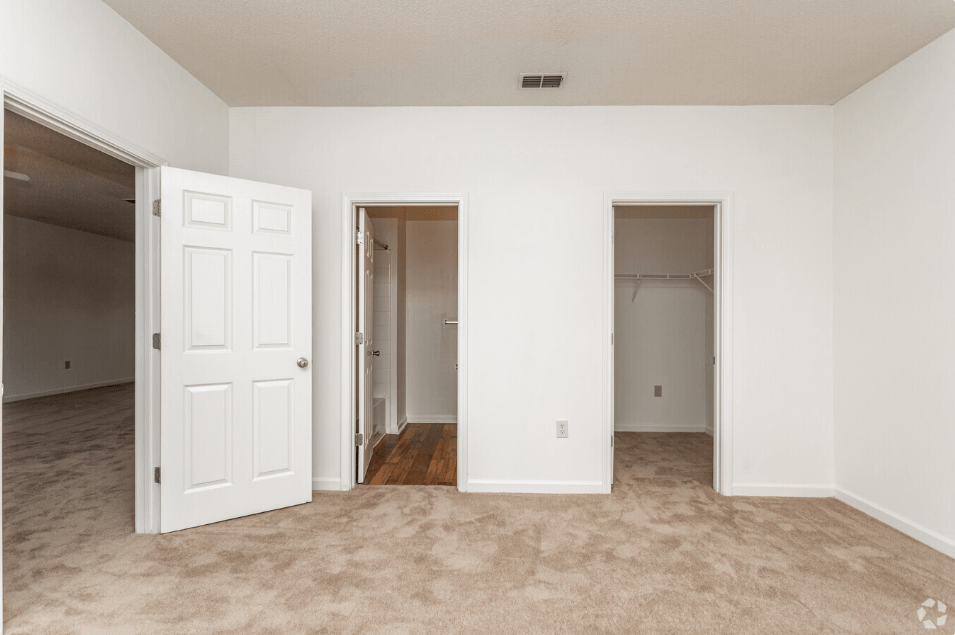 an empty living room with two doors and a closet