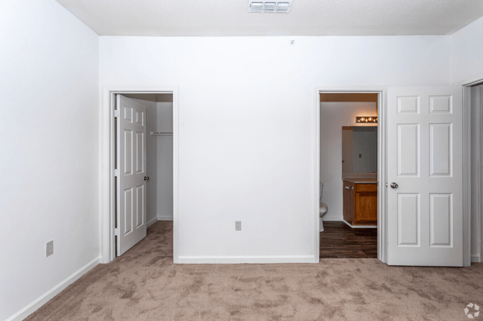 an empty living room with two doors and a bathroom